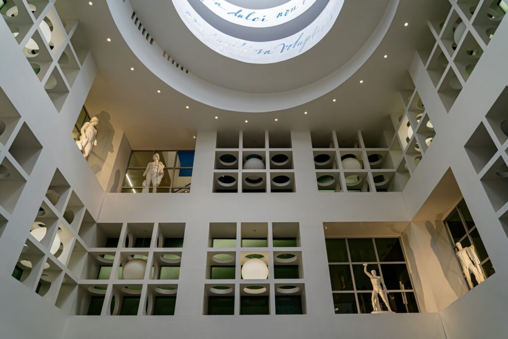 Vista verso l’alto della cupola bianca e delle statue classiche nell’area di Nettuno della stazione Chiaia – Monte di Dio.