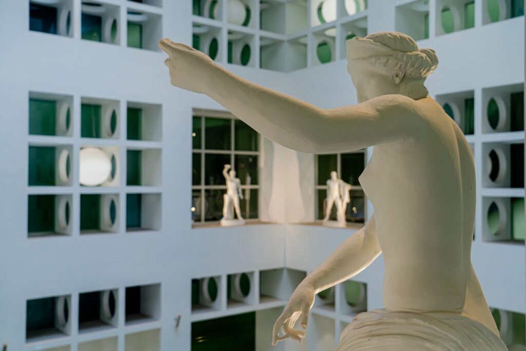 Statua classica bianca nella sezione di Cerere della stazione Chiaia – Monte di Dio, tra geometrie e luce naturale.