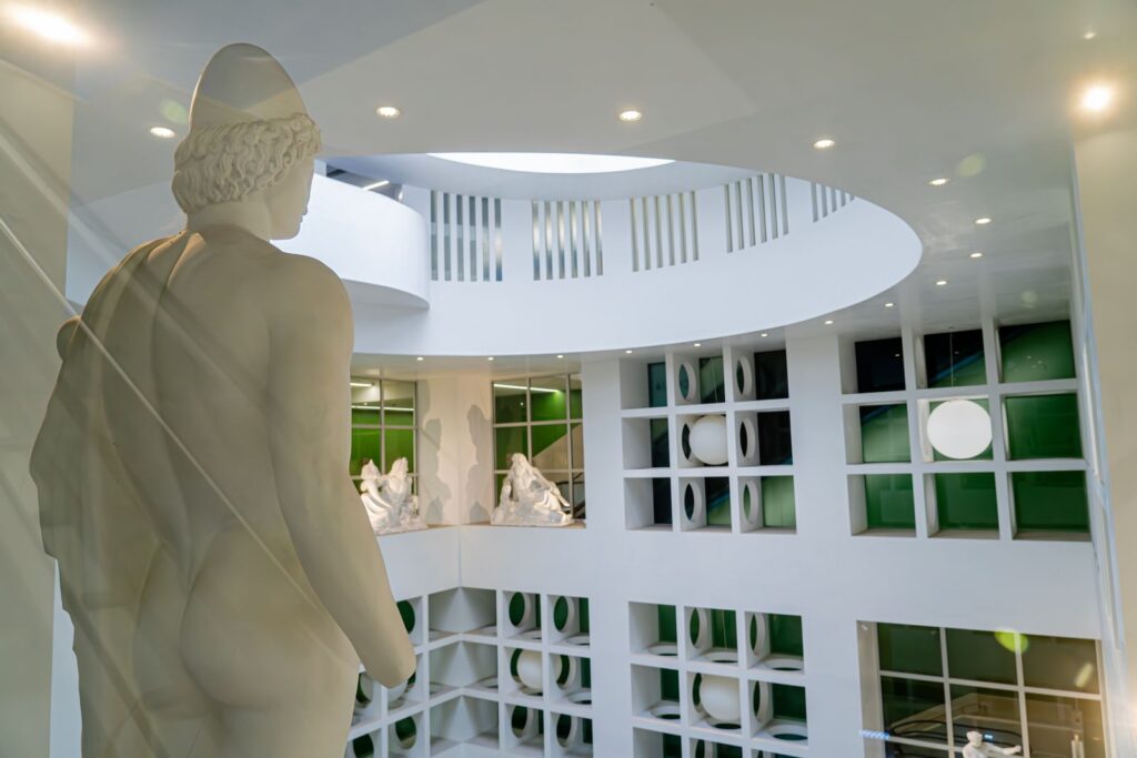 Statua classica affacciata sulla spirale di Nettuno nella stazione Chiaia – Monte di Dio, simbolo del viaggio negli abissi.