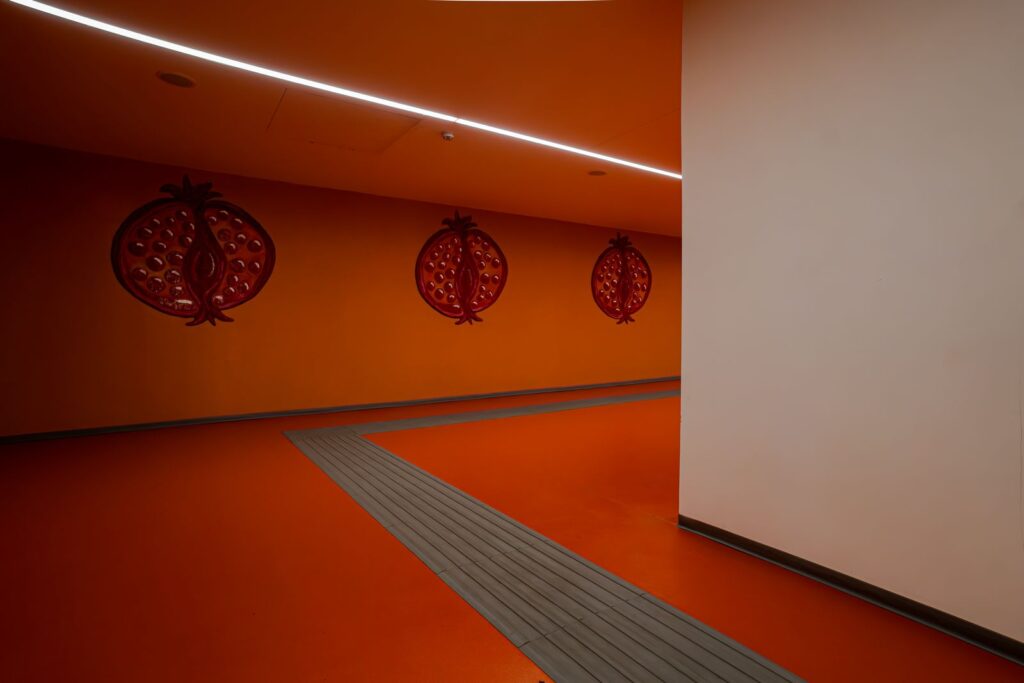 Corridoio arancione con melograni simbolici dedicati al mito di Proserpina nella stazione Chiaia – Monte di Dio.