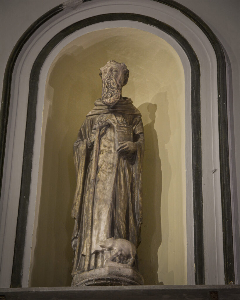 Statua di Sant’Antonio Abate raffigurata a figura intera con il maialino ai piedi, collocata in una nicchia della chiesa di Sant’Antonio Abate a Napoli