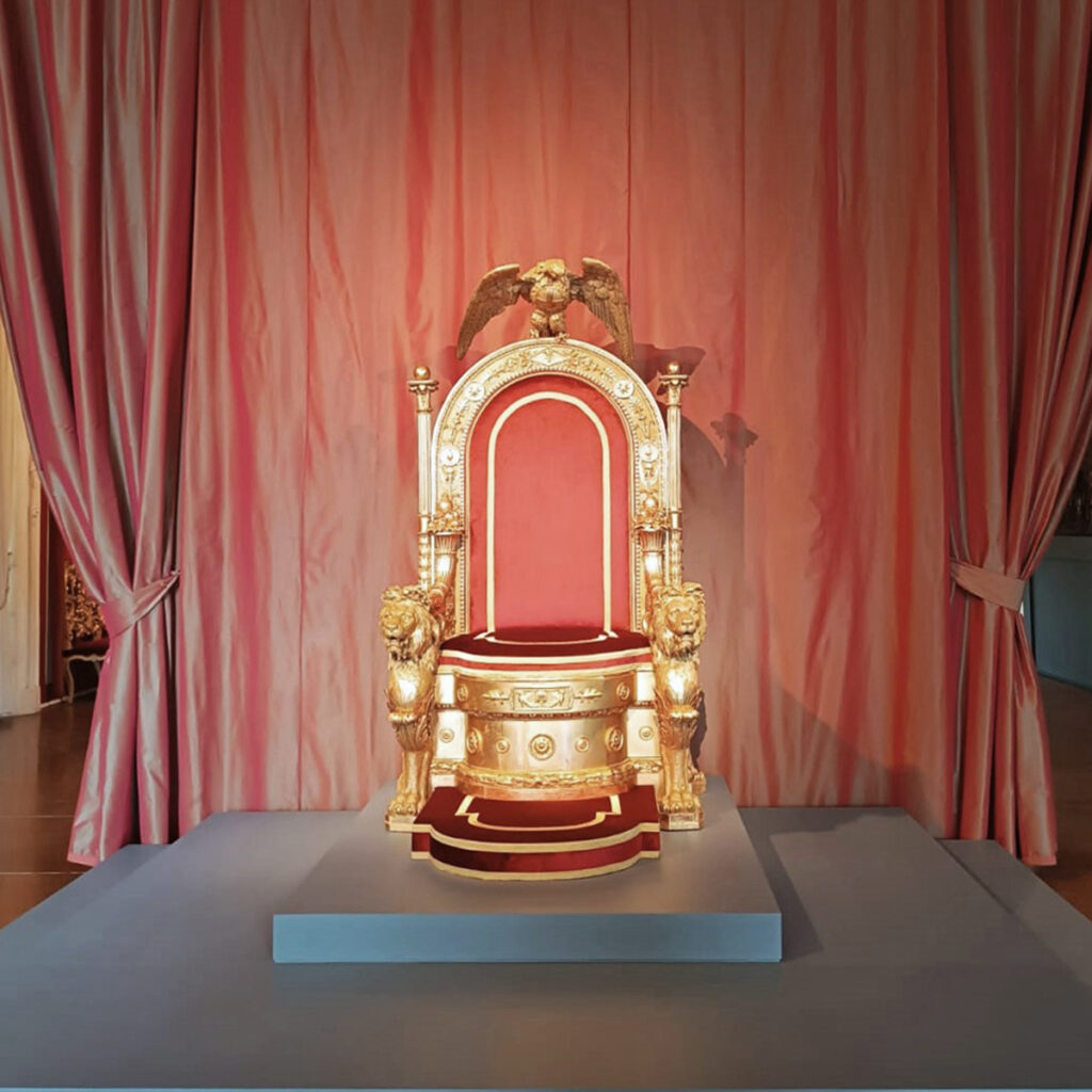 Il trono restaurato di Palazzo Reale a Napoli esposto nella Sala del Trono su pedana in velluto rosso.